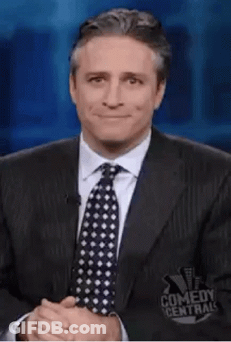 A Man In A Suit And Tie Is Making A Funny Face While Giving A Thumbs Up . GIF