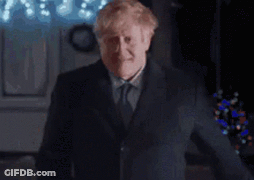 A Man In A Suit And Tie Is Making A Funny Face While Giving A Thumbs Up . GIF