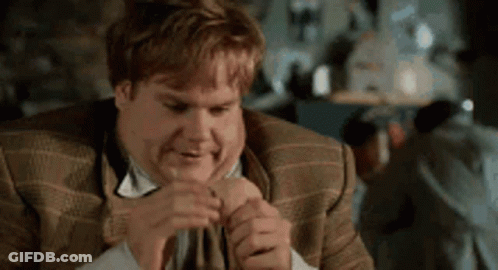 A Man In A Suit And Tie Is Making A Funny Face While Holding His Hand To His Face . GIF