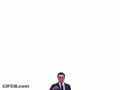 A Man In A Suit And Tie Is Making A Funny Face While Pointing At The Camera . GIF