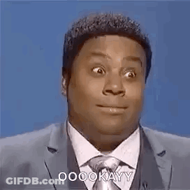 A Man In A Suit And Tie Is Making A Funny Face While Speaking Into A Microphone . GIF