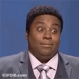 A Man In A Suit And Tie Is Making A Funny Face While Standing In Front Of A Blue Background . GIF