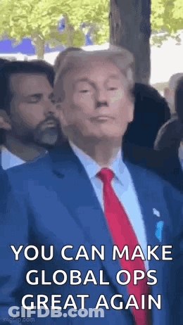 A Man In A Suit And Tie Is Making A Funny Face While Standing In Front Of A Crowd . GIF