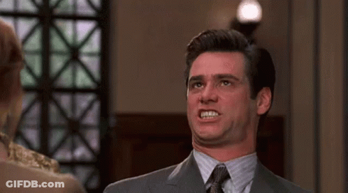 A Man In A Suit And Tie Is Making A Funny Face While Standing Next To A Woman . GIF