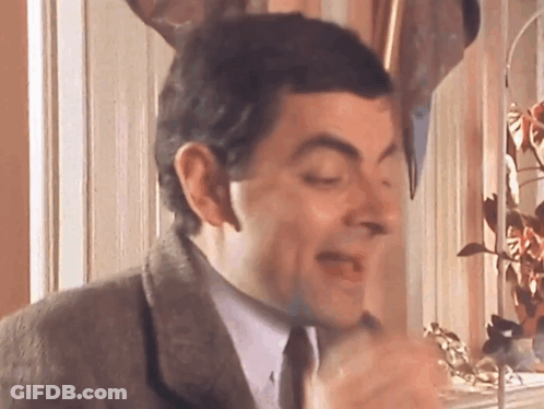 A Man In A Suit And Tie Is Making A Funny Face With His Eyes Closed GIF