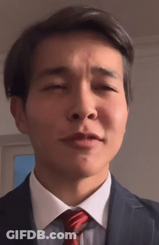 A Man In A Suit And Tie Is Making A Funny Face With His Eyes Closed GIF