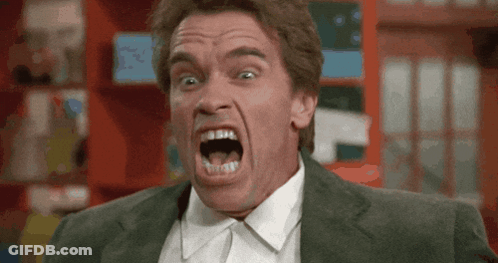 A Man In A Suit And Tie Is Making A Funny Face With His Mouth Open GIF