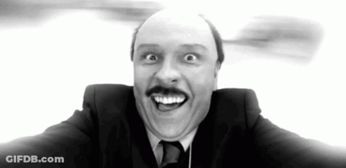 A Man In A Suit And Tie Is Making A Funny Face With His Mouth Open . GIF