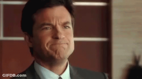 A Man In A Suit And Tie Is Making A Funny Face With His Mouth Open . GIF