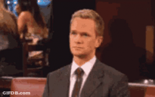 A Man In A Suit And Tie Is Making A Gesture With His Hand . GIF