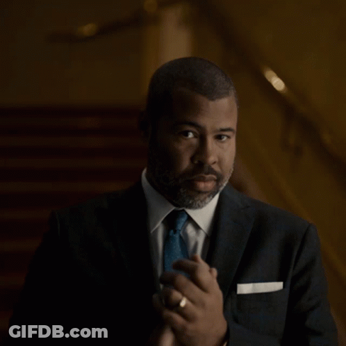 A Man In A Suit And Tie Is Making A Gesture GIF