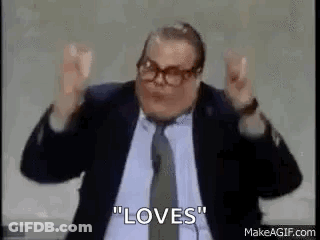 A Man In A Suit And Tie Is Making A Peace Sign With His Hands In The Air . GIF