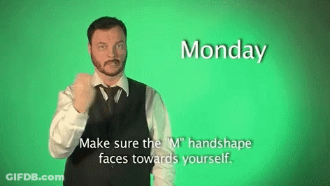 A Man In A Suit And Tie Is Making A Sign That Says Monday Make Sure The M Handshape Faces Towards Yourself GIF