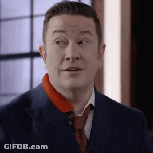 A Man In A Suit And Tie Is Making A Surprised Face . GIF