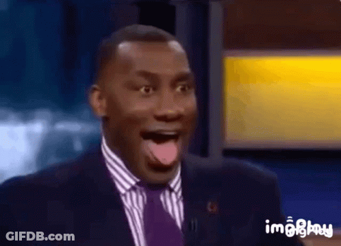 A Man In A Suit And Tie Is Making A Surprised Face With His Tongue Out . GIF
