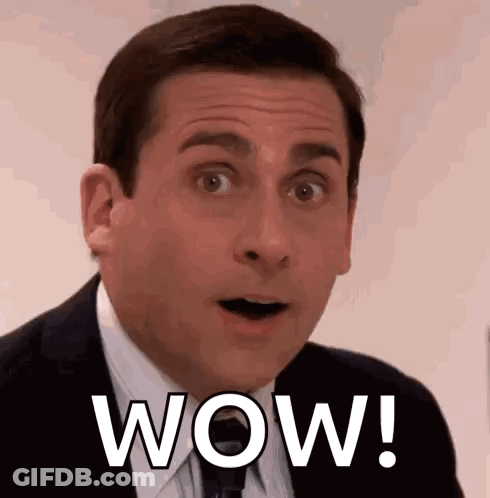 A Man In A Suit And Tie Is Making A Surprised Face With The Word Wow Written On His Face . GIF
