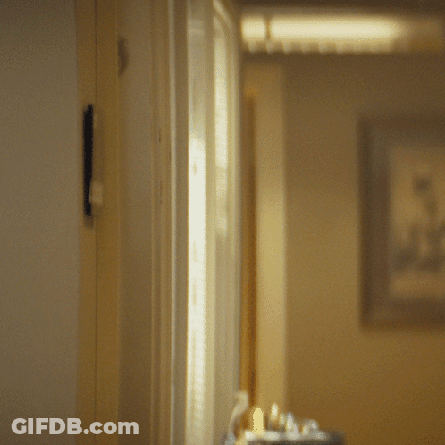 A Man In A Suit And Tie Is Peeking Through A Door GIF
