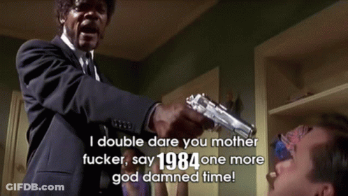 A Man In A Suit And Tie Is Pointing A Gun At Another Man With The Words " I Double Dare You Mother Fucker " Above Him GIF