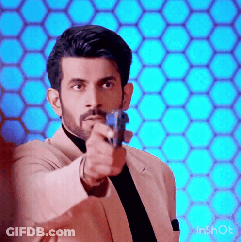 A Man In A Suit And Tie Is Pointing A Gun At Someone . GIF