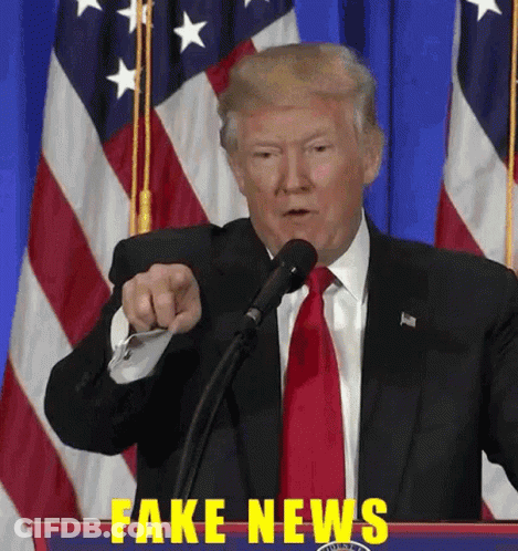 A Man In A Suit And Tie Is Pointing At A Microphone With Fake News Written In Yellow GIF