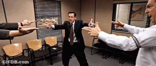 A Man In A Suit And Tie Is Pointing At Another Man In A White Shirt GIF