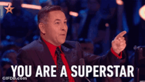 A Man In A Suit And Tie Is Pointing At Someone And Says You Are A Superstar . GIF