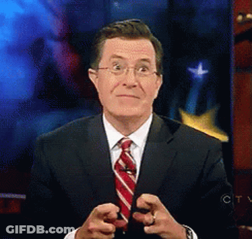 A Man In A Suit And Tie Is Pointing At Something GIF