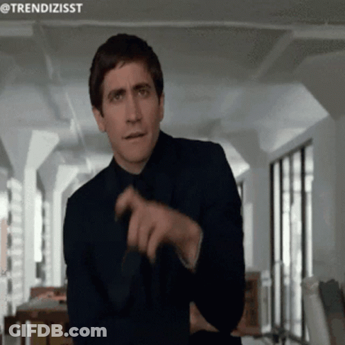 A Man In A Suit And Tie Is Pointing At Something With The Hashtag Trendizisst GIF