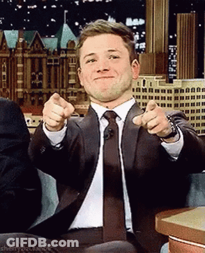 A Man In A Suit And Tie Is Pointing At The Camera With His Fingers . GIF