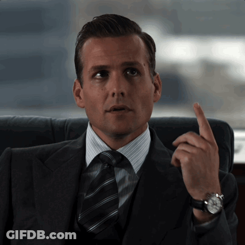 A Man In A Suit And Tie Is Pointing His Finger Up GIF