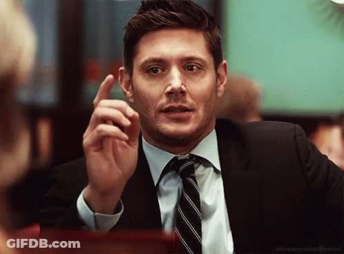 A Man In A Suit And Tie Is Pointing Up GIF