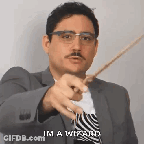 A Man In A Suit And Tie Is Pointing With A Wand And Saying `` Im A Wizard '' . GIF
