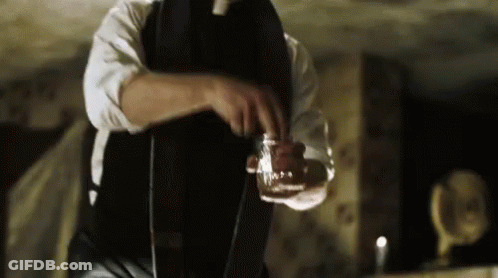 A Man In A Suit And Tie Is Pouring A Drink Into A Glass . GIF