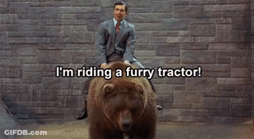 A Man In A Suit And Tie Is Riding A Furry Bear GIF