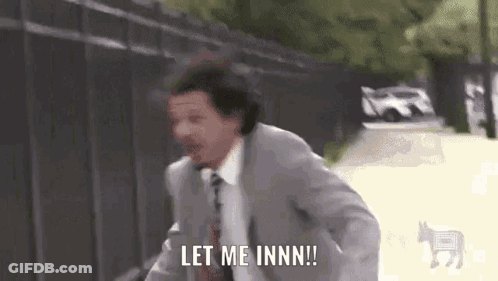 A Man In A Suit And Tie Is Running Down A Street And Saying `` Let Me Inn ! '' GIF