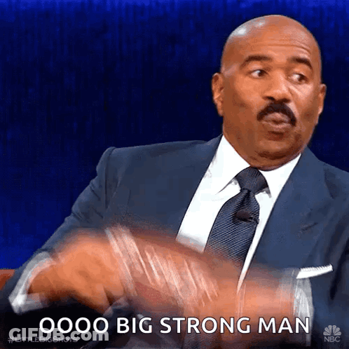 A Man In A Suit And Tie Is Saying " Oooo Big Strong Man " . GIF