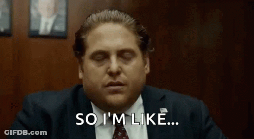 A Man In A Suit And Tie Is Saying `` So I 'M Like '' While Sitting At A Desk . GIF