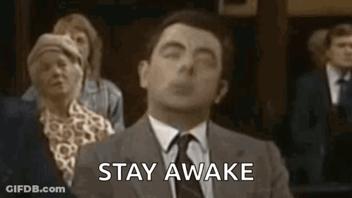A Man In A Suit And Tie Is Saying `` Stay Awake '' While Sitting In Front Of A Group Of People . GIF