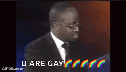 A Man In A Suit And Tie Is Saying `` U Are Gay '' With Rainbows In The Background . GIF