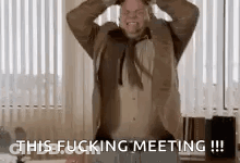A Man In A Suit And Tie Is Screaming And Holding His Head In A Room . GIF