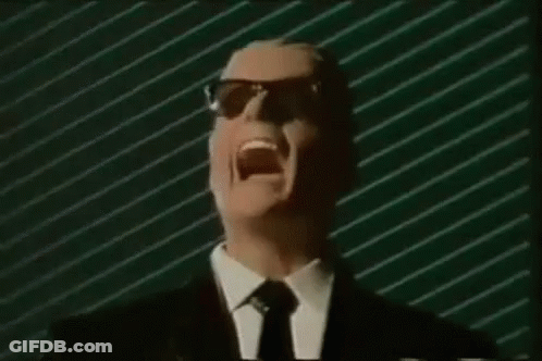 A Man In A Suit And Tie Is Screaming In Front Of A Green Striped Wall . GIF