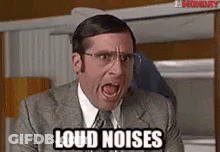 A Man In A Suit And Tie Is Screaming With The Words `` Loud Noises '' Written On His Face . GIF