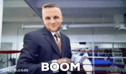 A Man In A Suit And Tie Is Shaking Hands In A Boxing Ring And The Word Boom Is On The Bottom GIF