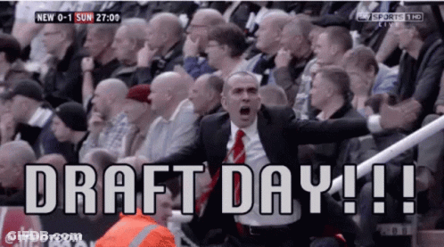 A Man In A Suit And Tie Is Shouting In Front Of A Crowd That Says Draft Day ! GIF