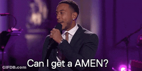 A Man In A Suit And Tie Is Singing Into A Microphone And Asking Can I Get A Amen . GIF