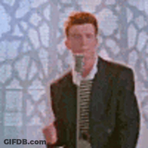 A Man In A Suit And Tie Is Singing Into A Microphone In Front Of A Wall . GIF