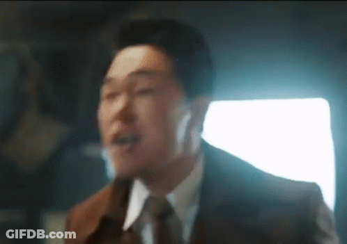 A Man In A Suit And Tie Is Singing Into A Microphone While Wearing Headphones . GIF