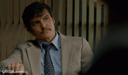 A Man In A Suit And Tie Is Sitting At A Desk GIF