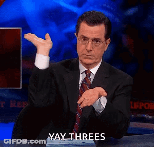 A Man In A Suit And Tie Is Sitting At A Desk And Making A Funny Face While Saying Yay Threes . GIF