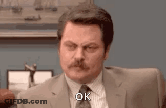 A Man In A Suit And Tie Is Sitting At A Desk And Making An Ok Sign . GIF